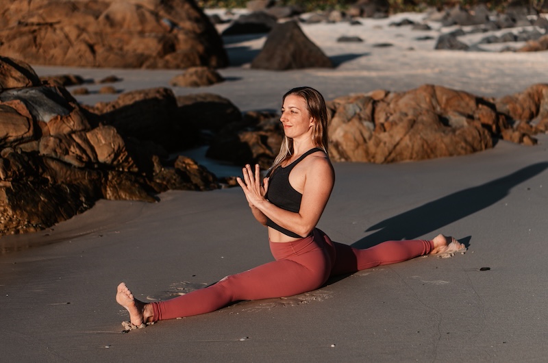 yogi practising hanumanasana on the beach